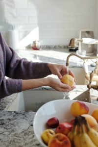 woman washing peach in the sink